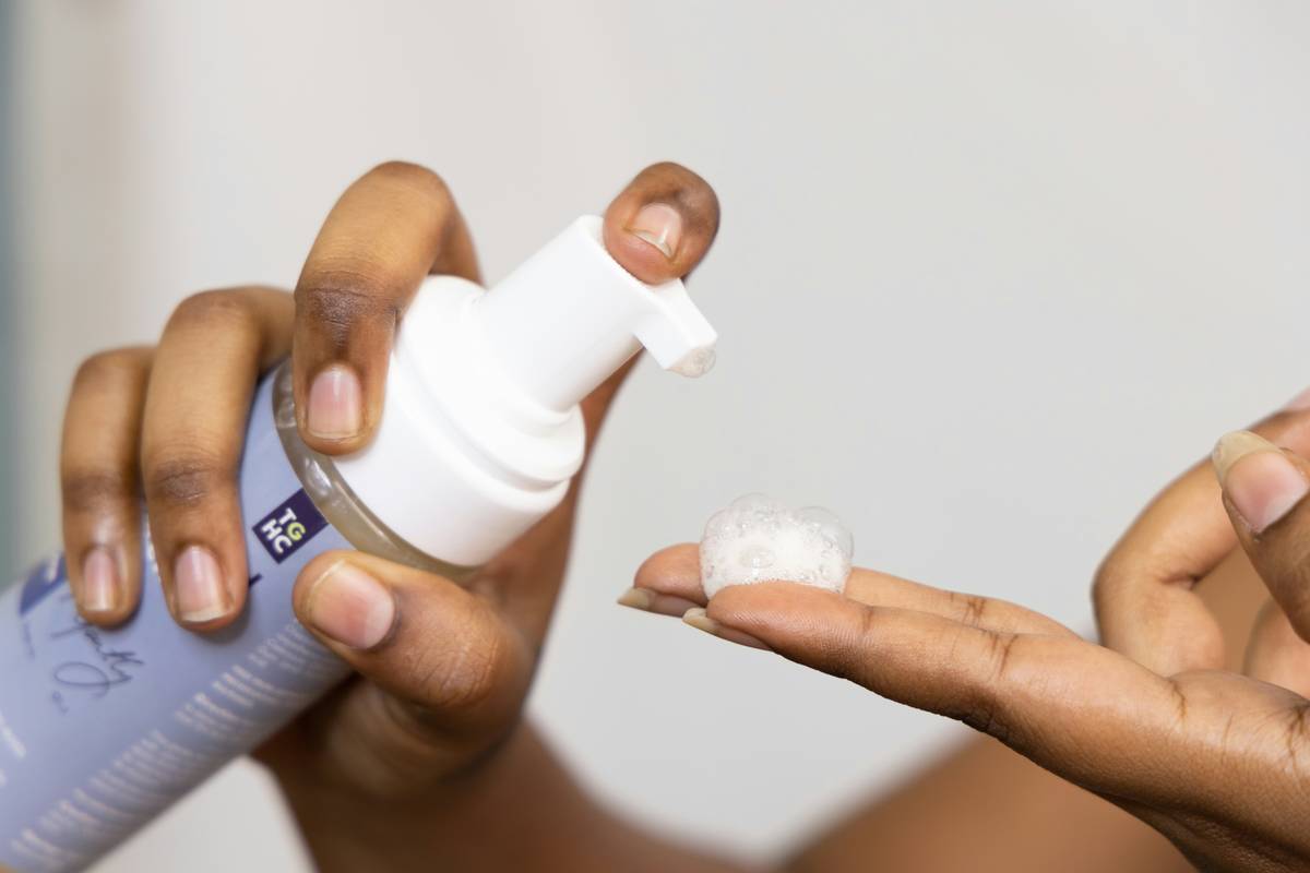 Woman applying organic facial cleansers for acne to her face with gentle circular motions