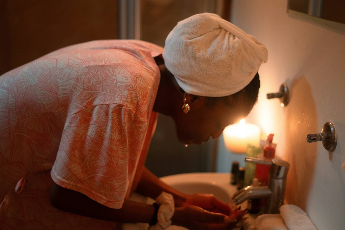 Woman applying gentle exfoliating cleanser for sensitive skin with fingertips on damp face in natural light